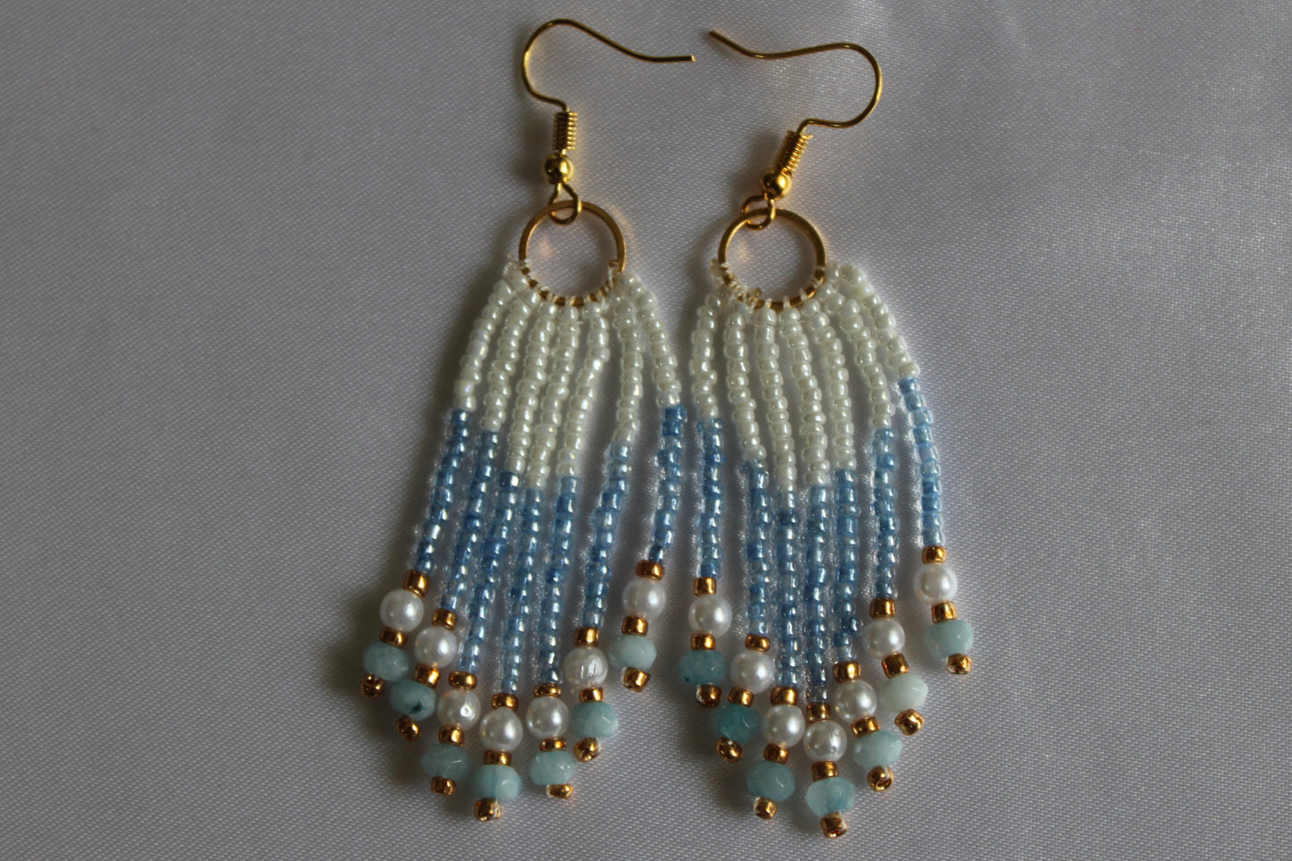 Handmade white and sky-blue beaded fringe earrings with pearl accents, cascading tassel design, gold-tone hoop connectors, and fish hook ear wires, lightweight boho dangle jewellery.