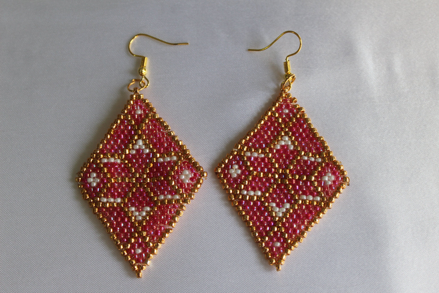 Handmade diamond-shaped seed bead earrings in pink, gold, and white featuring a geometric woven design with gold-tone fish hook ear wires, lightweight boho statement jewellery.