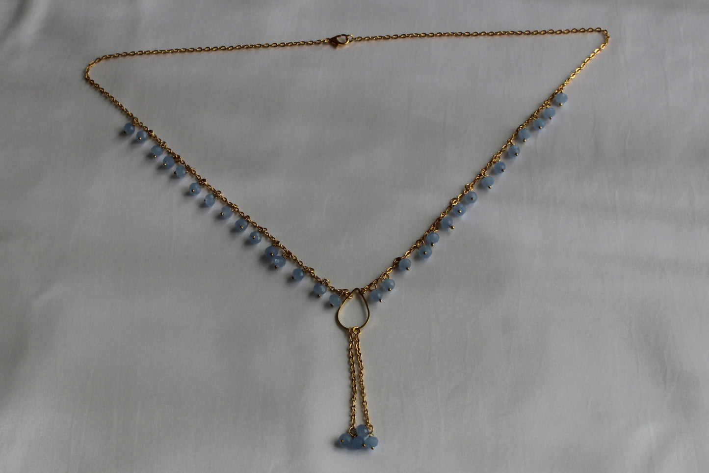 Handmade sky blue beaded Y necklace with gold-tone chain and elegant lariat drop pendant displayed on a white background.