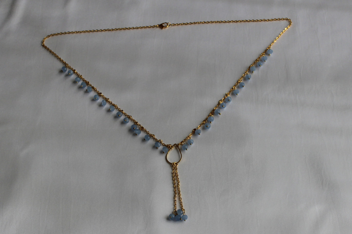 Handmade sky blue beaded Y necklace with gold-tone chain and elegant lariat drop pendant displayed on a white background.